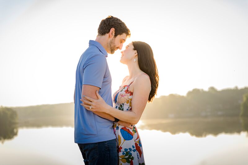 Theresa and Ryan close together, nose to nose, at golden hour beside a still lake