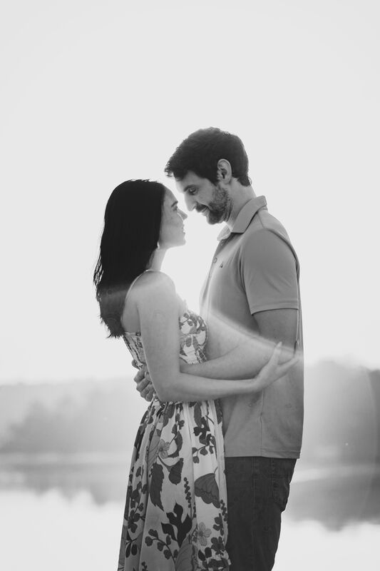 Theresa and Ryan embracing forehead to forehead in a black-and-white portrait by the water