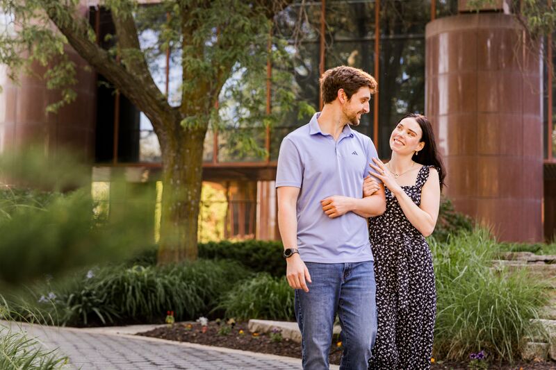 Theresa and Ryan walking arm in arm through a courtyard garden